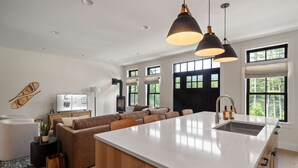 Una cocina moderna con una isla grande, iluminación colgante y vistas al exterior.