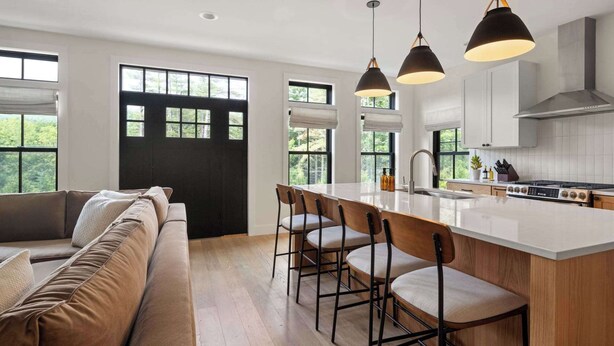 Una cocina moderna con una isla central, taburetes de bar e iluminación colgante.