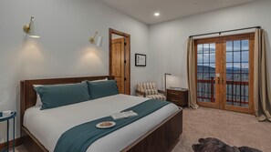 A bedroom with a bed, a chair, a desk, and a view through a glass door. - 12 Bedrooms | Private Hot Tubs | Private Ski Shuttle | Apex Grande (Steamboat Springs)