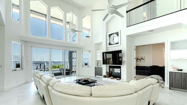 A spacious living area with a large white sectional sofa, a fireplace, and a ceiling fan.