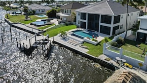 A residential property with a swimming pool, dock, and a large house with a modern design.