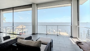 A balcony with wicker furniture and a view of the sea.