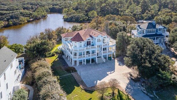 Ein großes, mehrstöckiges Haus mit einer umlaufenden Veranda und Blick auf einen Fluss.