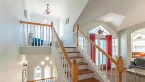 Ein mehrgeschossiges Interieur mit Holztreppen, weißen Geländern und Blick ins Freie.