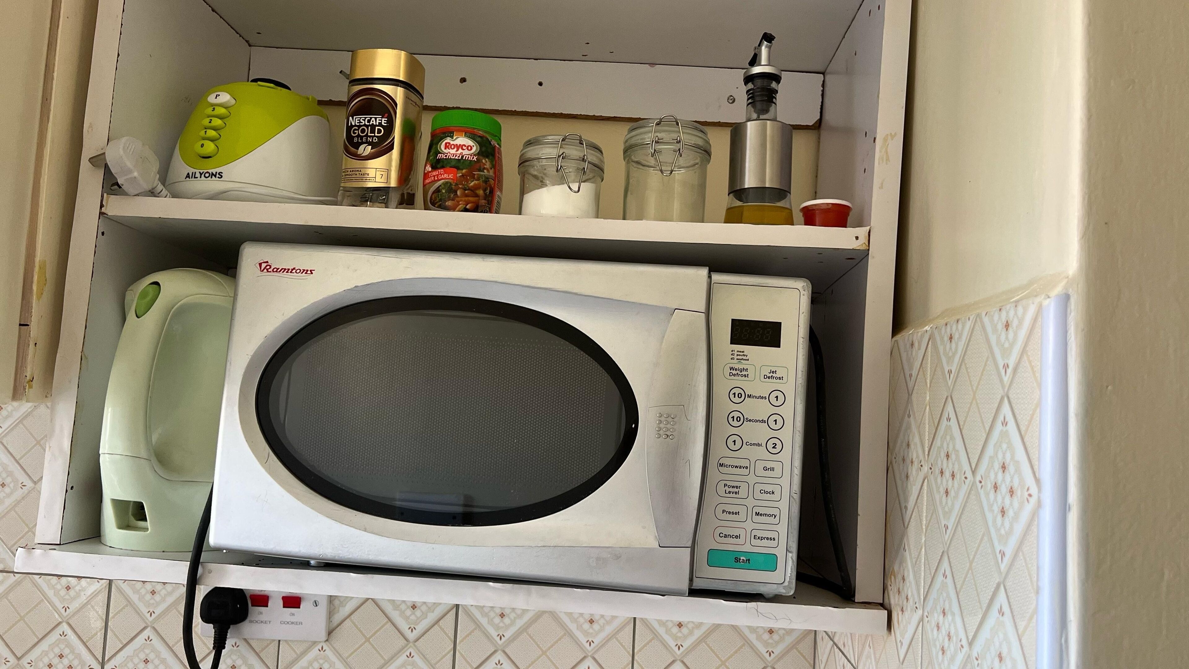 A kitchen with a microwave, a phone, and various kitchen items on shelves.
