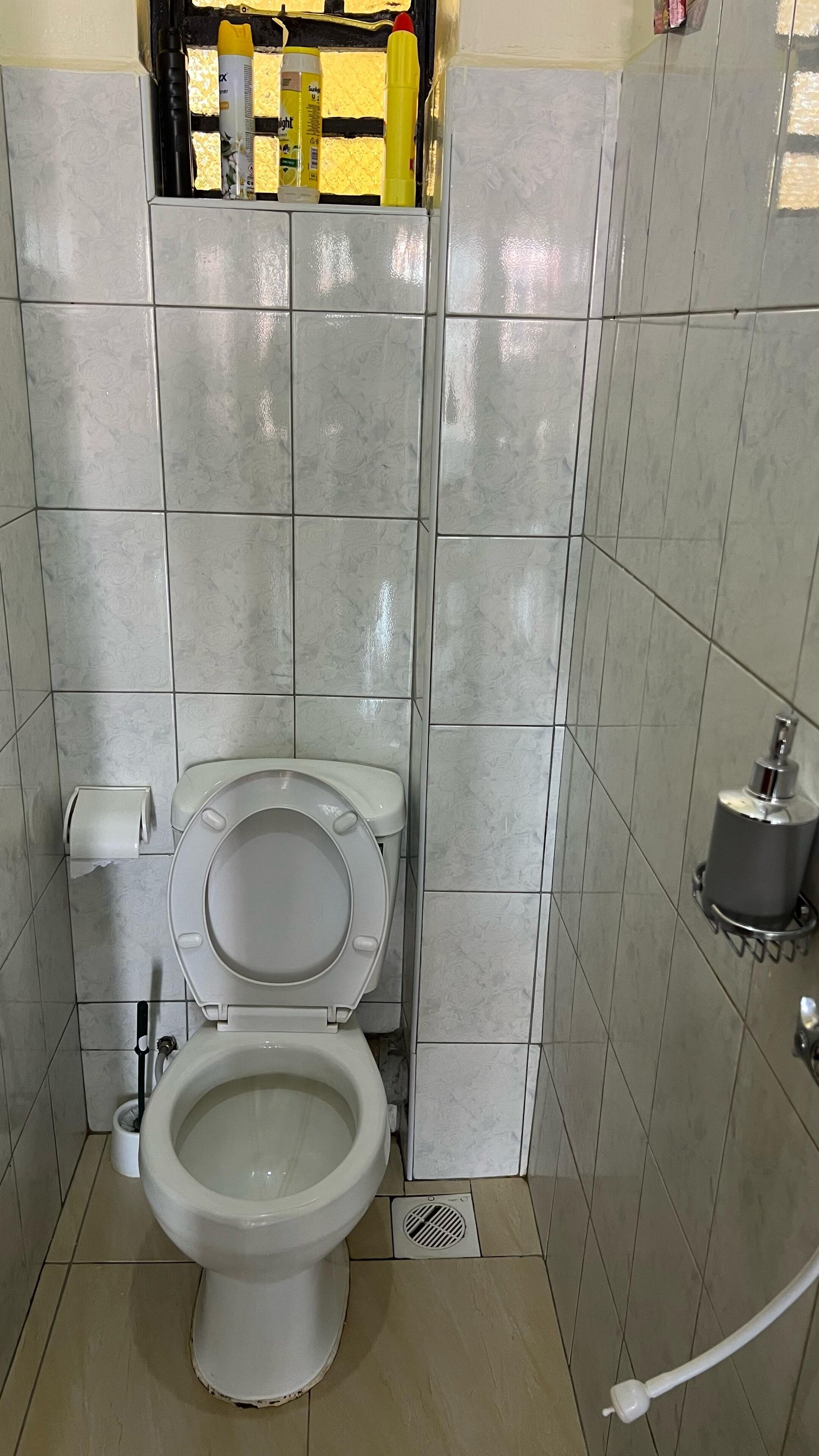 Et badeværelse med toilet, håndtørrer og papirhåndklædedispenser.