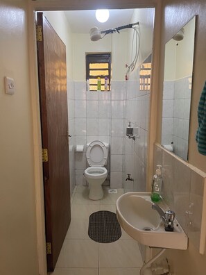 Kylpyhuone, jossa on wc, pesuallas, suihku ja pieni ikkuna.