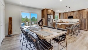 Une cuisine moderne avec des meubles en bois, un îlot central et un coin repas comprenant une longue table et des chaises.
