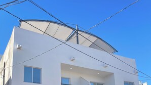 A two-story building with a garage, a car parked inside, and a clear blue sky. - 2-bedroom 2ba apartment in nuevo Mexicali -Up to 7 Guest (Mexicali)