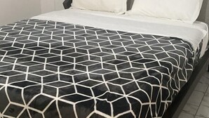 A bed with a geometric patterned bedspread, two pillows, and a wooden headboard. - 2-bedroom 2ba apartment in nuevo Mexicali -Up to 7 Guest (Mexicali)