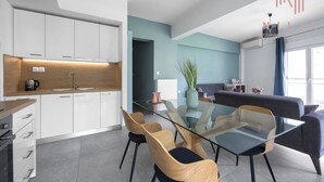 Une cuisine moderne avec des meubles blancs, une table à manger en verre et des chaises en bois.