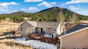 A house with a deck, a hot tub, and a mountain in the background.