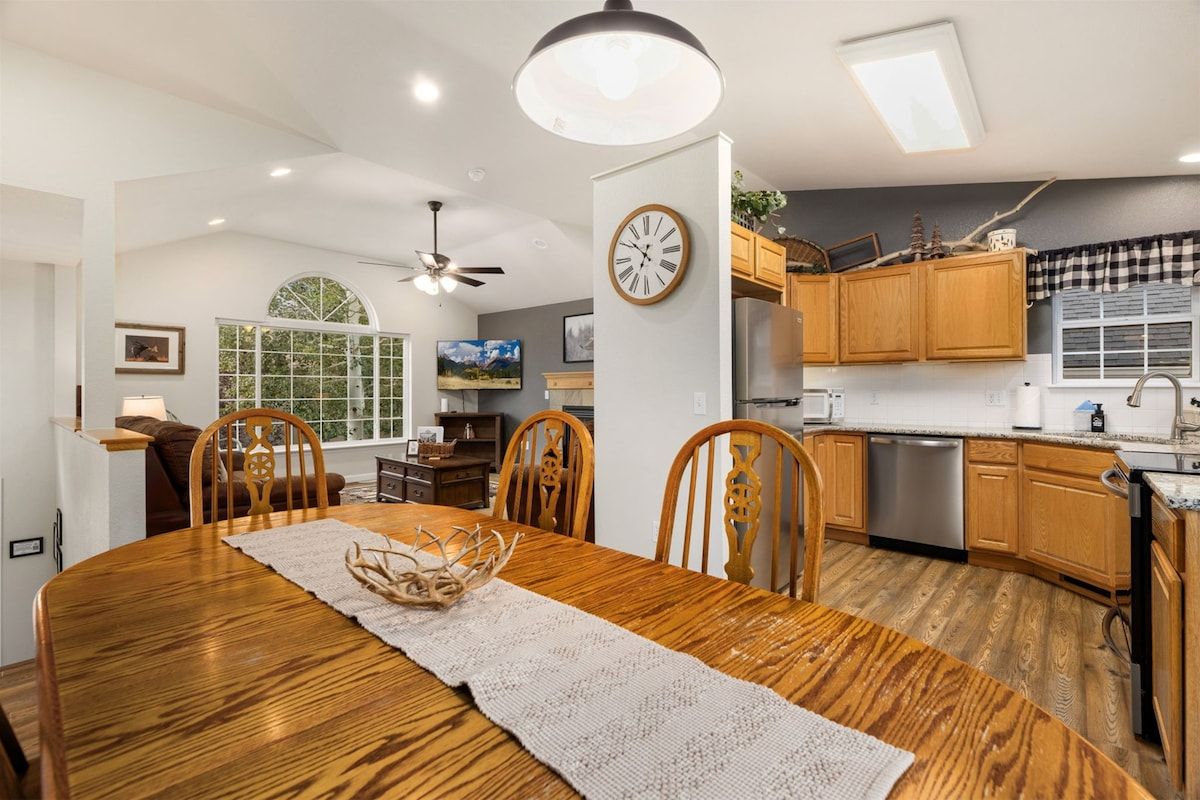 A dining area with a wooden table, chairs, and a clock on the wall.