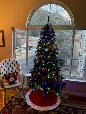 Un sapin de Noël illuminé, placé dans une pièce dotée d’une grande fenêtre.