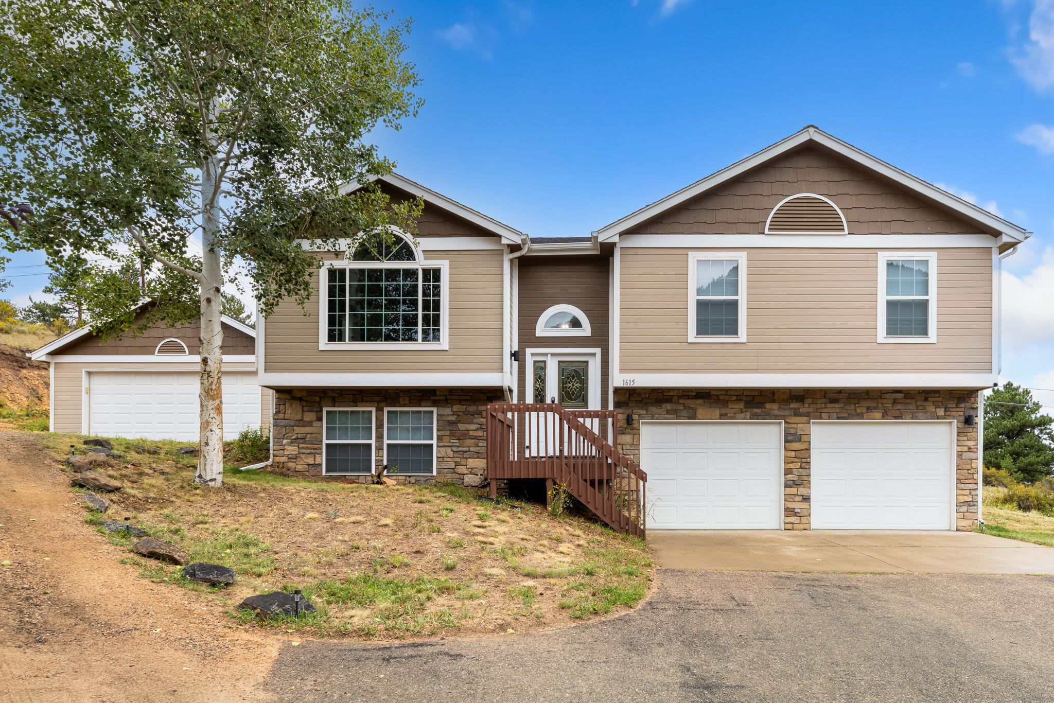 A two-story house with a stone facade, a front porch, and a driveway.