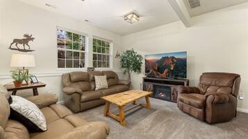 A living room with a brown leather sofa, a wooden coffee table, a recliner, a television, and a fireplace.