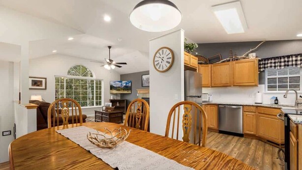 Une cuisine moderne avec des meubles en bois, un four encastré et un coin repas comprenant une table et des chaises en bois.