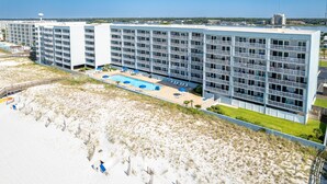 A modern hotel with multiple floors, a pool, and a beachside location. - Islander Beach Resort 302 Condo by RedAwning (Fort Walton Beach)