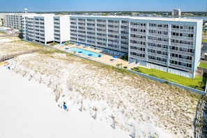 A multi-story hotel with a pool and beach access.