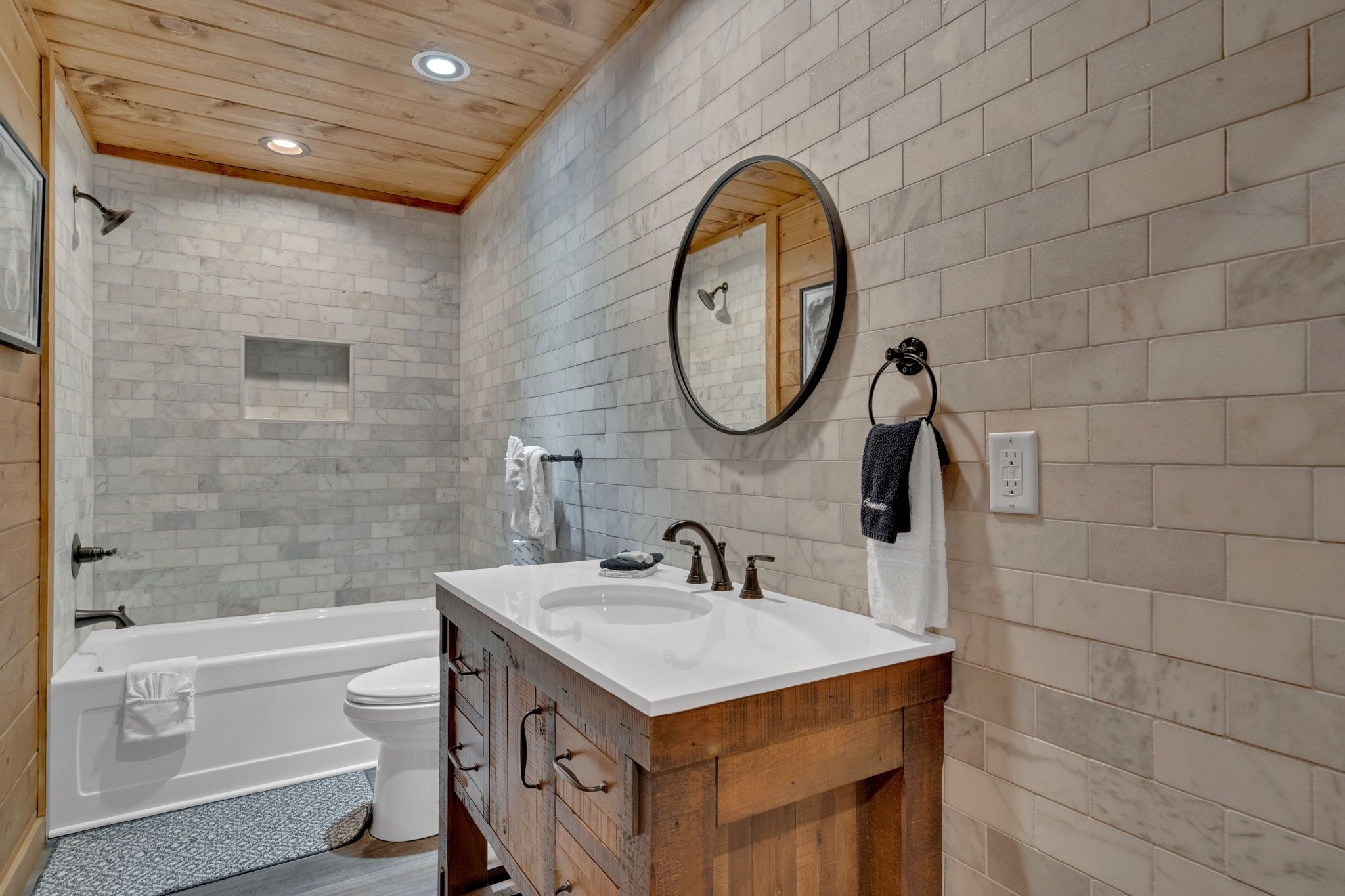 A bathroom with a wooden vanity, a white sink, a mirror, and a bathtub.