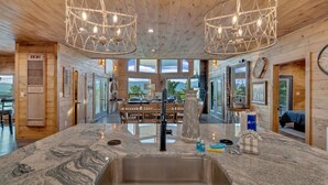 A kitchen with a granite countertop, stainless steel sink, and pendant lights.