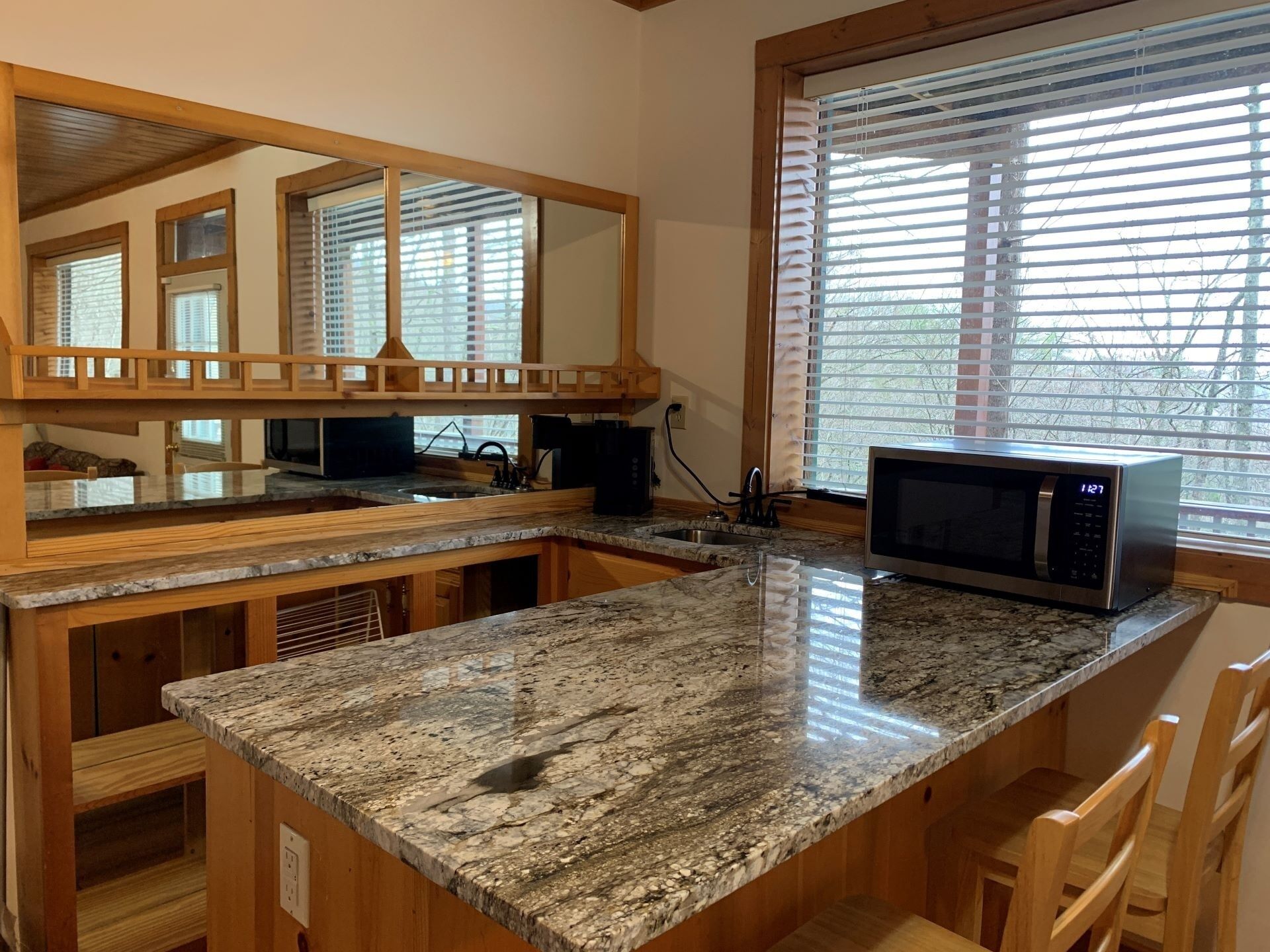 A kitchen with granite countertops, a built-in microwave, and wooden cabinetry.
