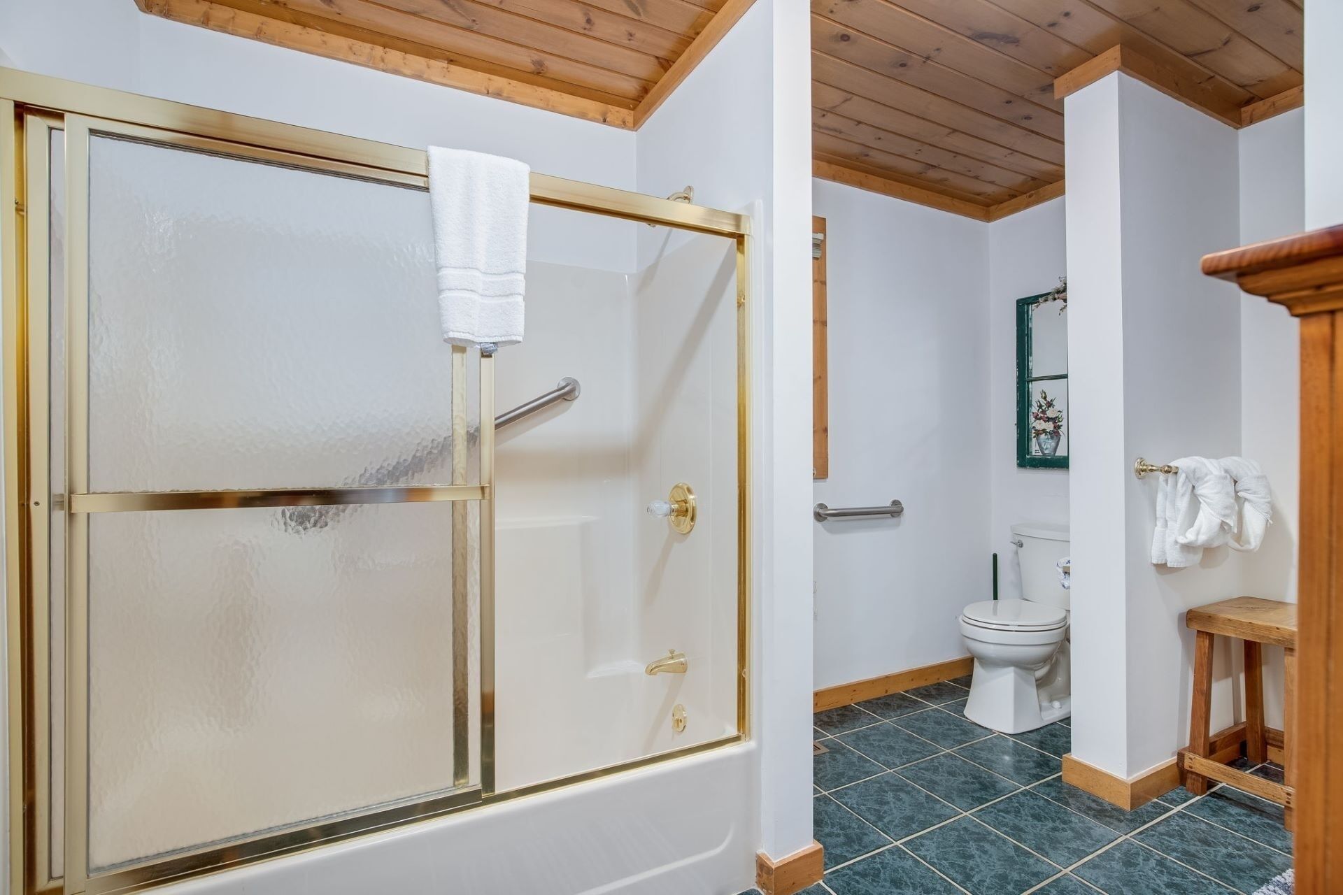 A bathroom with a glass shower enclosure, a toilet, and a sink.