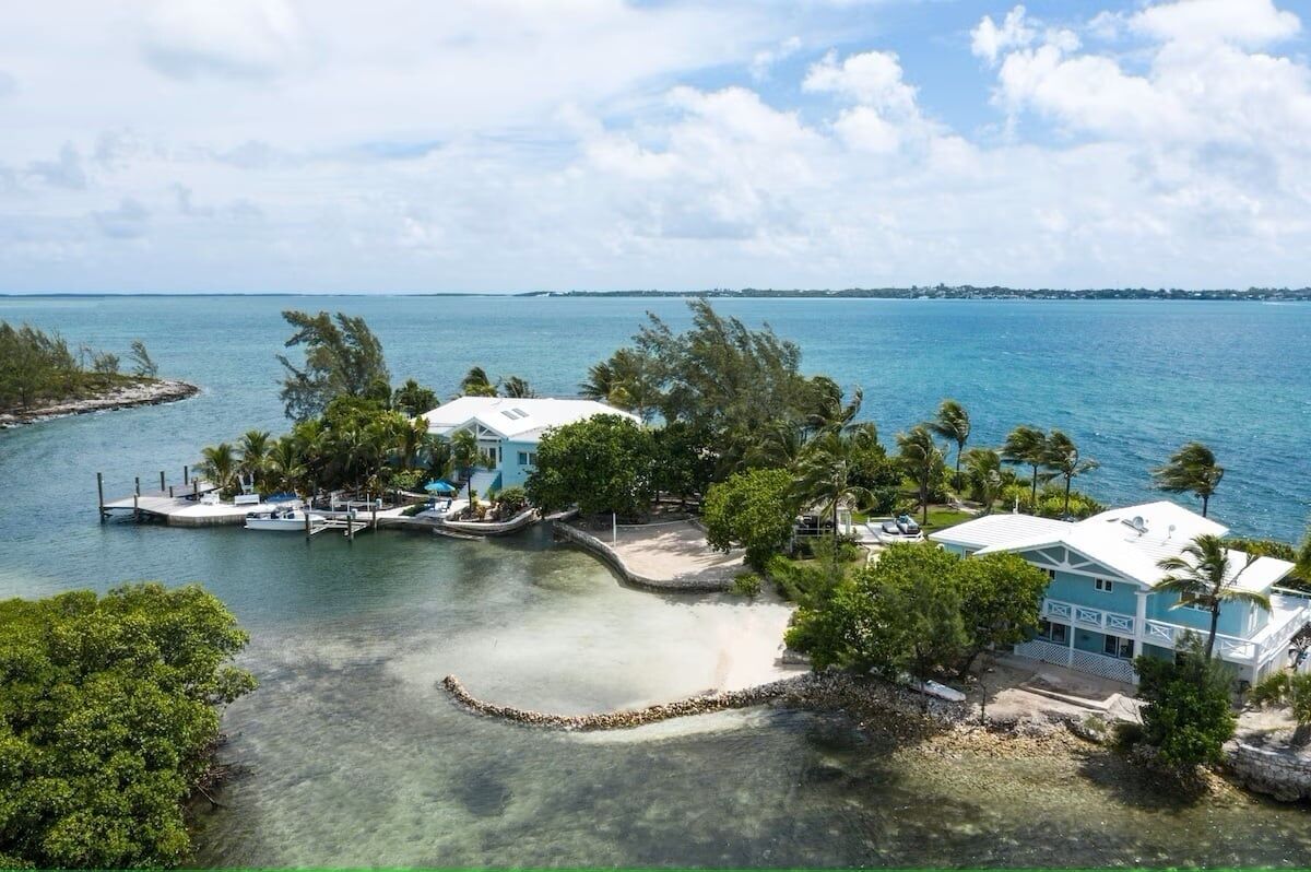 A coastal property with a dock, clear waters, and lush greenery.