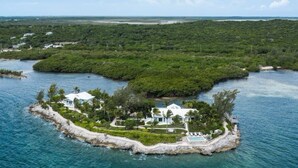 An aerial view of a private island with a white house surrounded by lush greenery and a clear blue sea. - Middle Cay Estate 7 Bedroom Estate (Middle Cay)