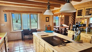 Una cocina amplia con armarios de madera, una isla grande con fregadero y una zona de comedor con mesa y sillas.