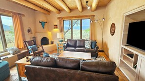 Una sala de estar acogedora con chimenea, sofás de cuero y un televisor sobre un mueble de madera.
