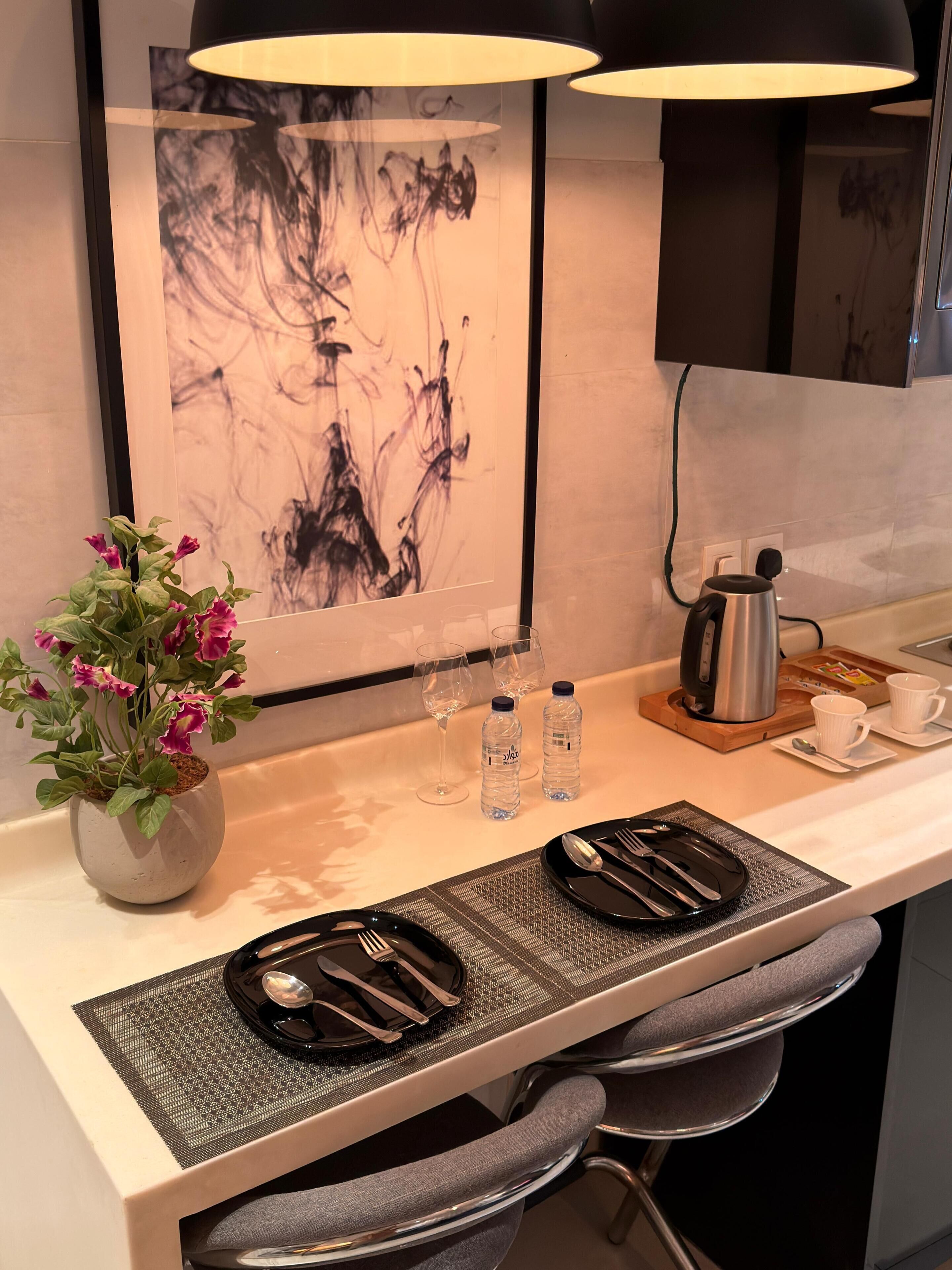 A modern kitchen with a dining area, a coffee maker, and a painting on the wall.