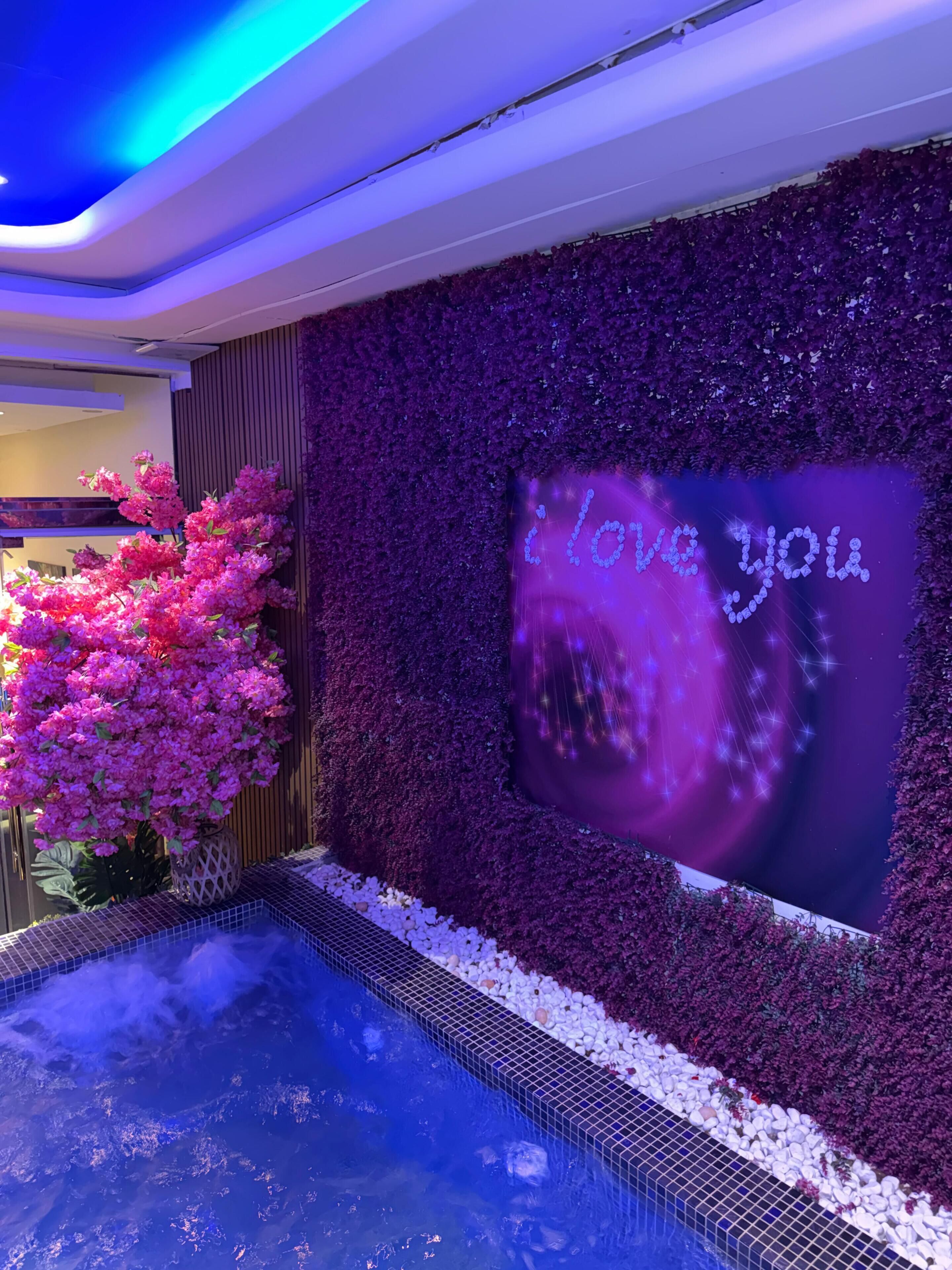 A wall with a 'I love you' message and a decorative pink flower arrangement.