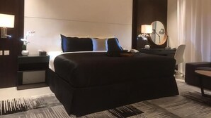 Ένα σύγχρονο δωμάτιο ξενοδοχείου με ένα μεγάλο κρεβάτι, κομοδίνα, ένα γραφείο και μια καρέκλα.