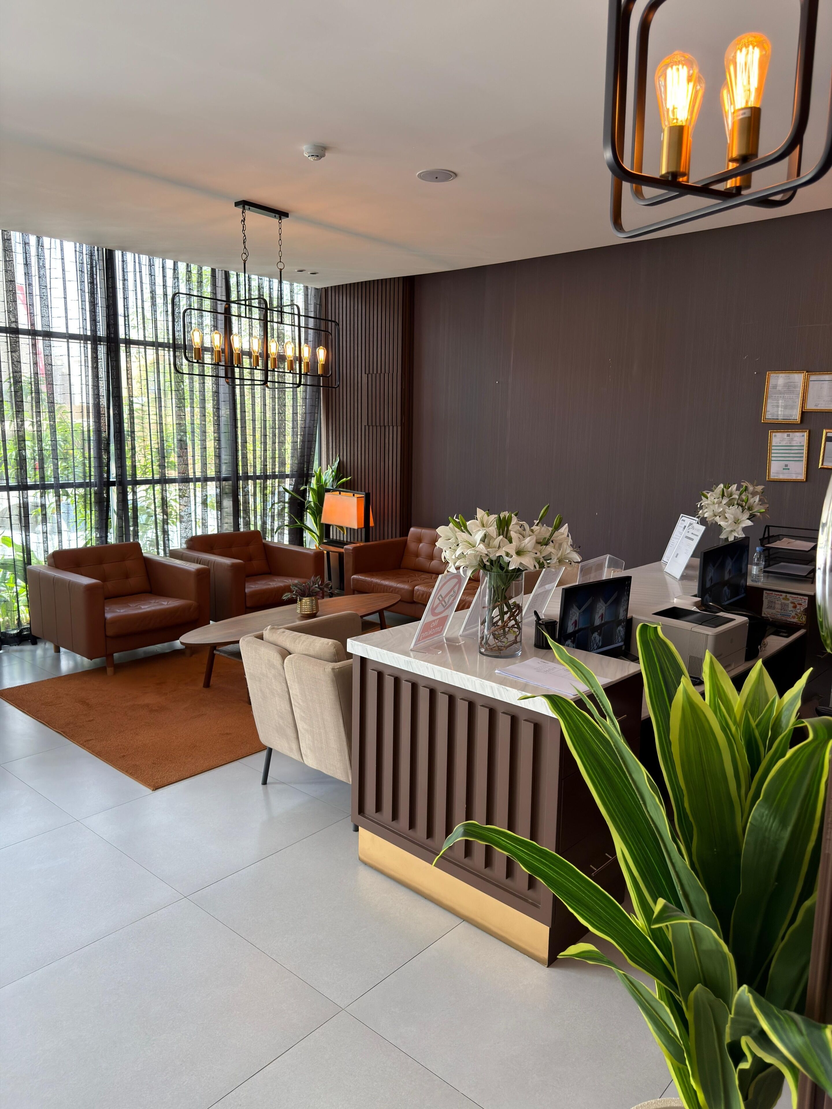 A modern reception area with a desk, seating, and a view through large windows.