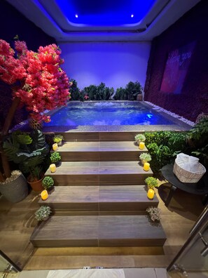 A pool area with steps leading to a hot tub, surrounded by plants and candles. - دانة للشقق المخدومة 1 - Dana Serviced Apartment (Riyadh)