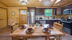 A wooden cabin interior with a dining table set for six, a refrigerator, a microwave, and a dishwasher. - 4/4 Cabin w 4 King Suites|Hot Tub|Views 5 min to Gatlinburg! (Gatlinburg)