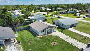 A residential area with single-story houses, well-maintained lawns, and a clear sky. - Welcome to Casa del Sol! Charming 2 bedroom home located 4 miles from the beach! (Englewood)