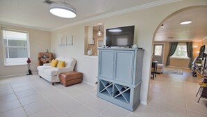 A spacious living room with a large blue cabinet, a white sofa, and a television on top. - Welcome to Casa del Sol! Charming 2 bedroom home located 4 miles from the beach! (Englewood)