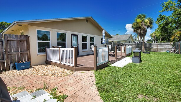 A single-story house with a deck, a fenced backyard, and a palm tree. - Welcome to Casa del Sol! Charming 2 bedroom home located 4 miles from the beach! (Englewood)