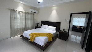 A modern bedroom with a bed, bedside tables, a ceiling fan, and an air conditioning unit. - Amore Villa Retreat in Ocho Rios (Ocho Rios)