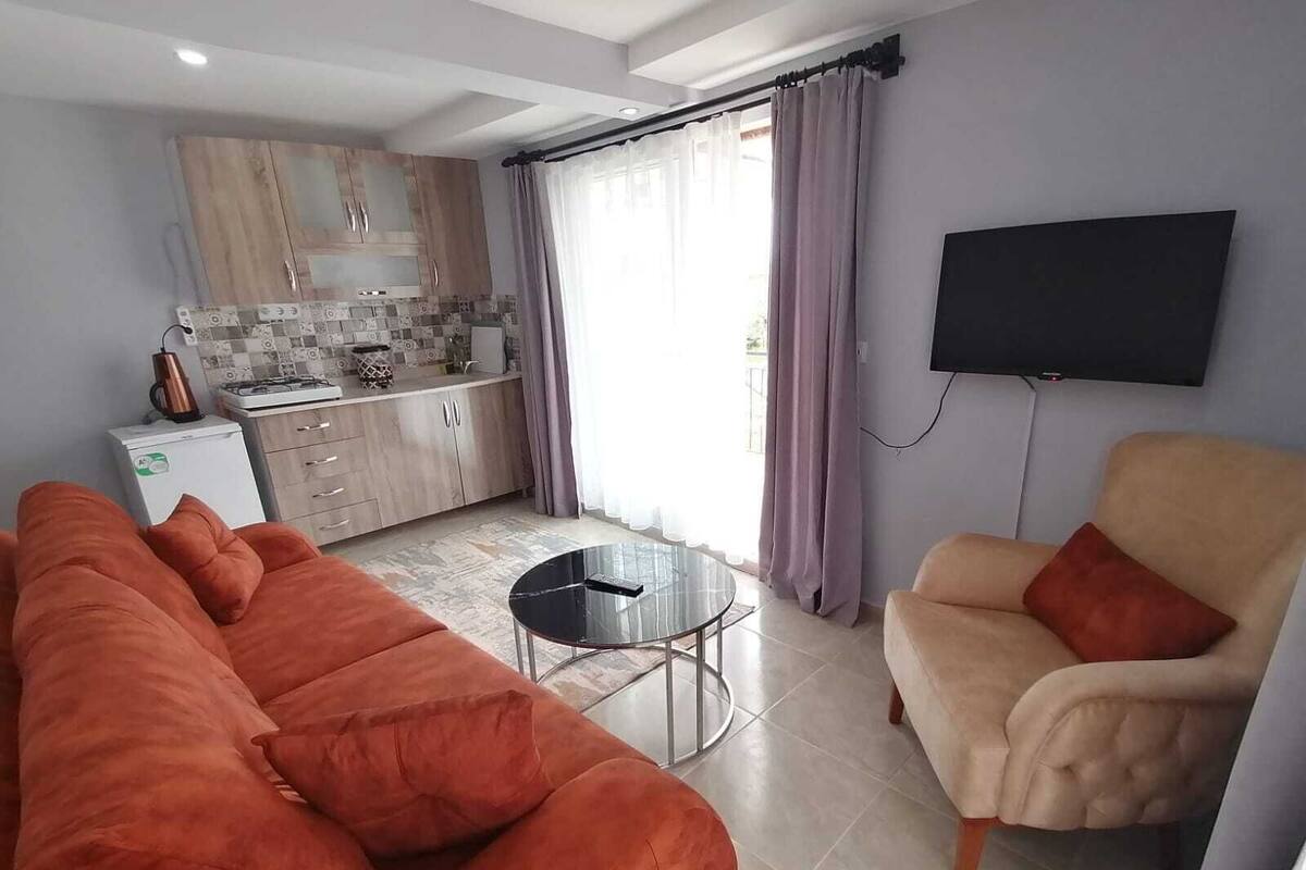 A modern living room with a sofa, a chair, a small coffee table, and a kitchen in the background.
