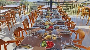 A long dining table set outdoors with chairs, plates, and various food items. - Habesa Bungalov & Apart (Kas)