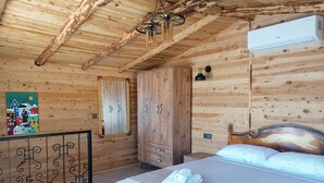 A wooden cabin bedroom with a bed, a wardrobe, and a painting on the wall. - Habesa Bungalov & Apart (Kas)
