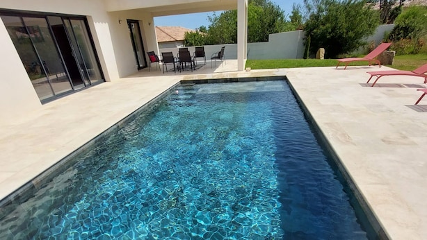 A rectangular swimming pool with clear blue water, surrounded by a tiled deck. - Villa Venturon Proche la Plage de Pinarello Avec Piscine et Cuisine D'été (Zonza)