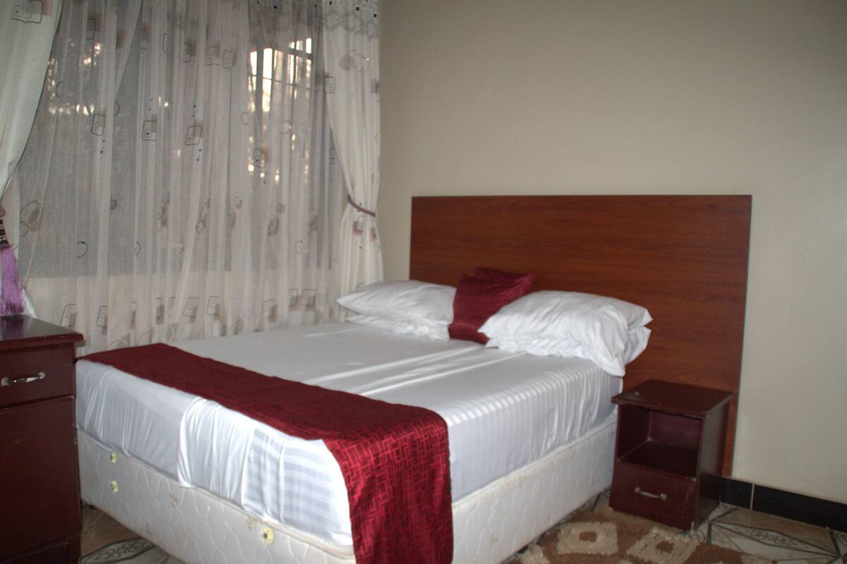 A neatly made bed with a wooden headboard, a bedside table, and a nightstand.