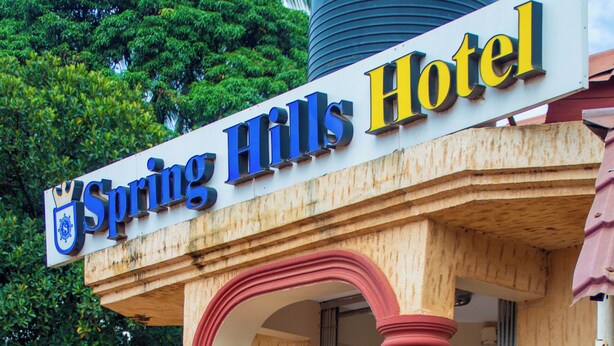 L’entrée d’un hôtel, avec une enseigne indiquant « Spring Hills Hotel ».