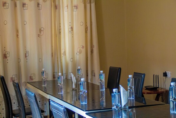 A conference room with a glass table, chairs, water bottles, and a curtain with a geometric pattern.