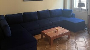 Un saló amb un sofà seccional blau fosc, una taula de centre de fusta i una obra d'art abstracta emmarcada a la paret.