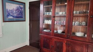 Une cuisine avec un meuble en bois contenant de la vaisselle et des verres.